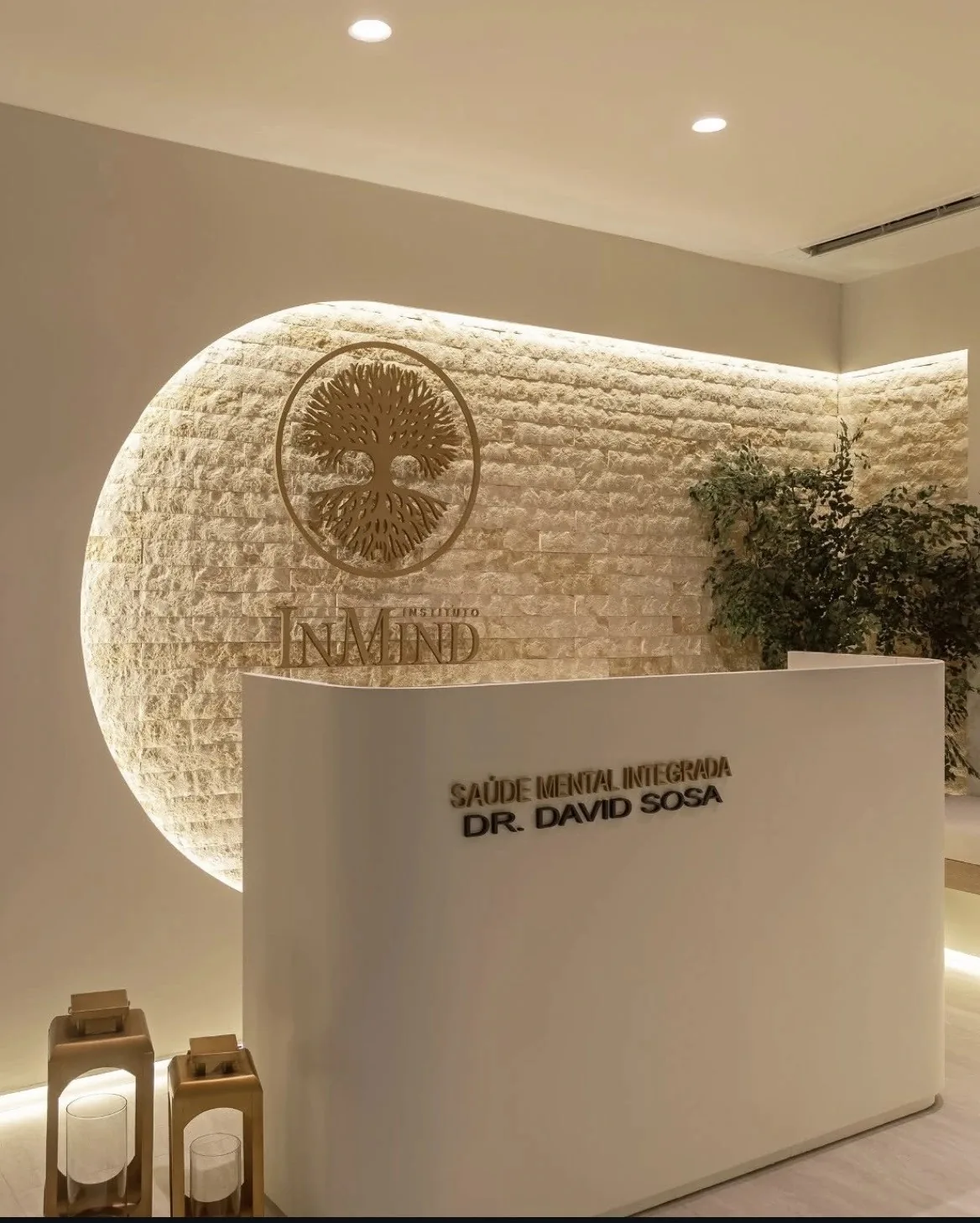 Recepção do Instituto InMind, em Botafogo, com parede de pedra iluminada e balcão branco