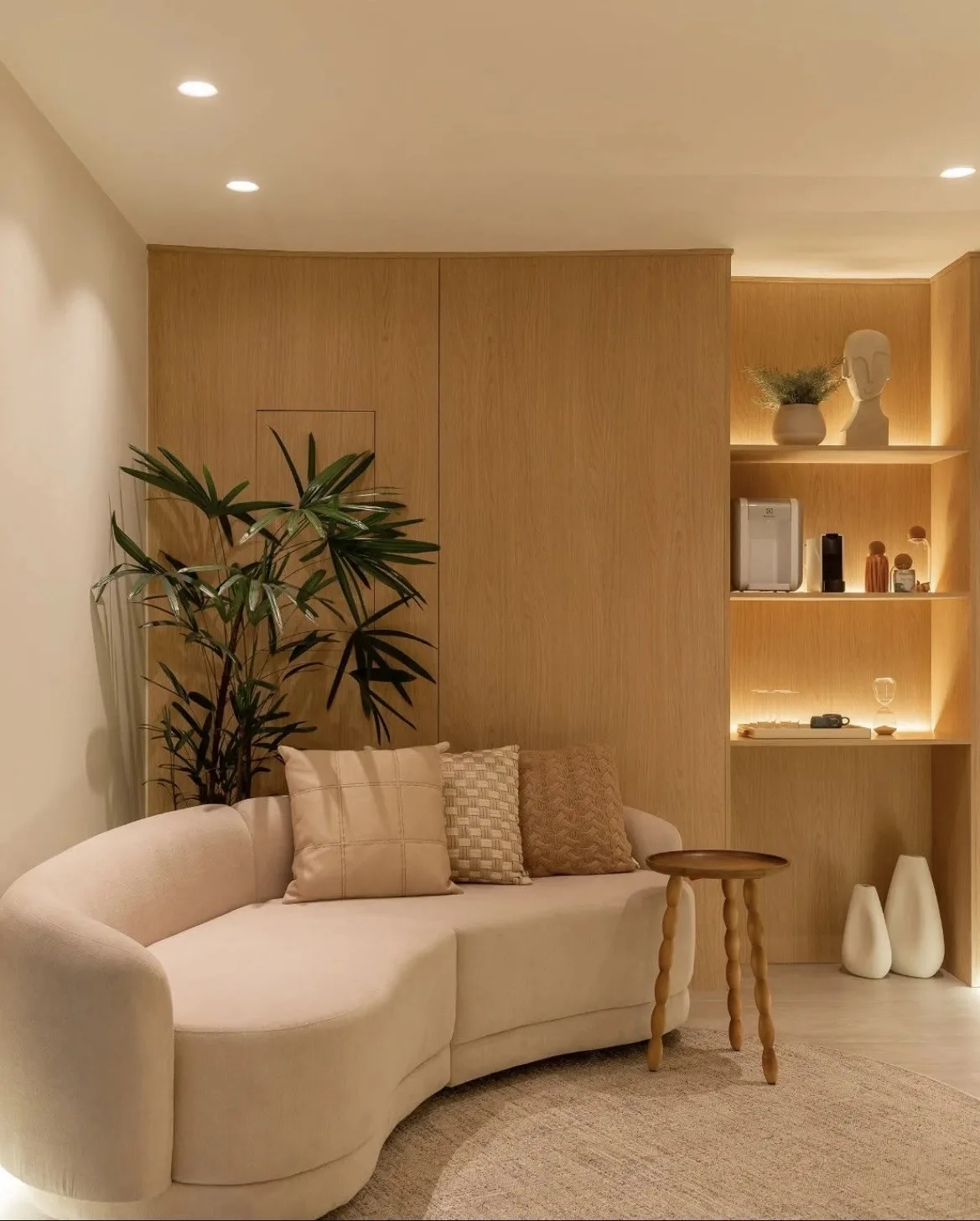 Sala de espera do Instituto InMind, com sofá claro, plantas e estante de madeira iluminada